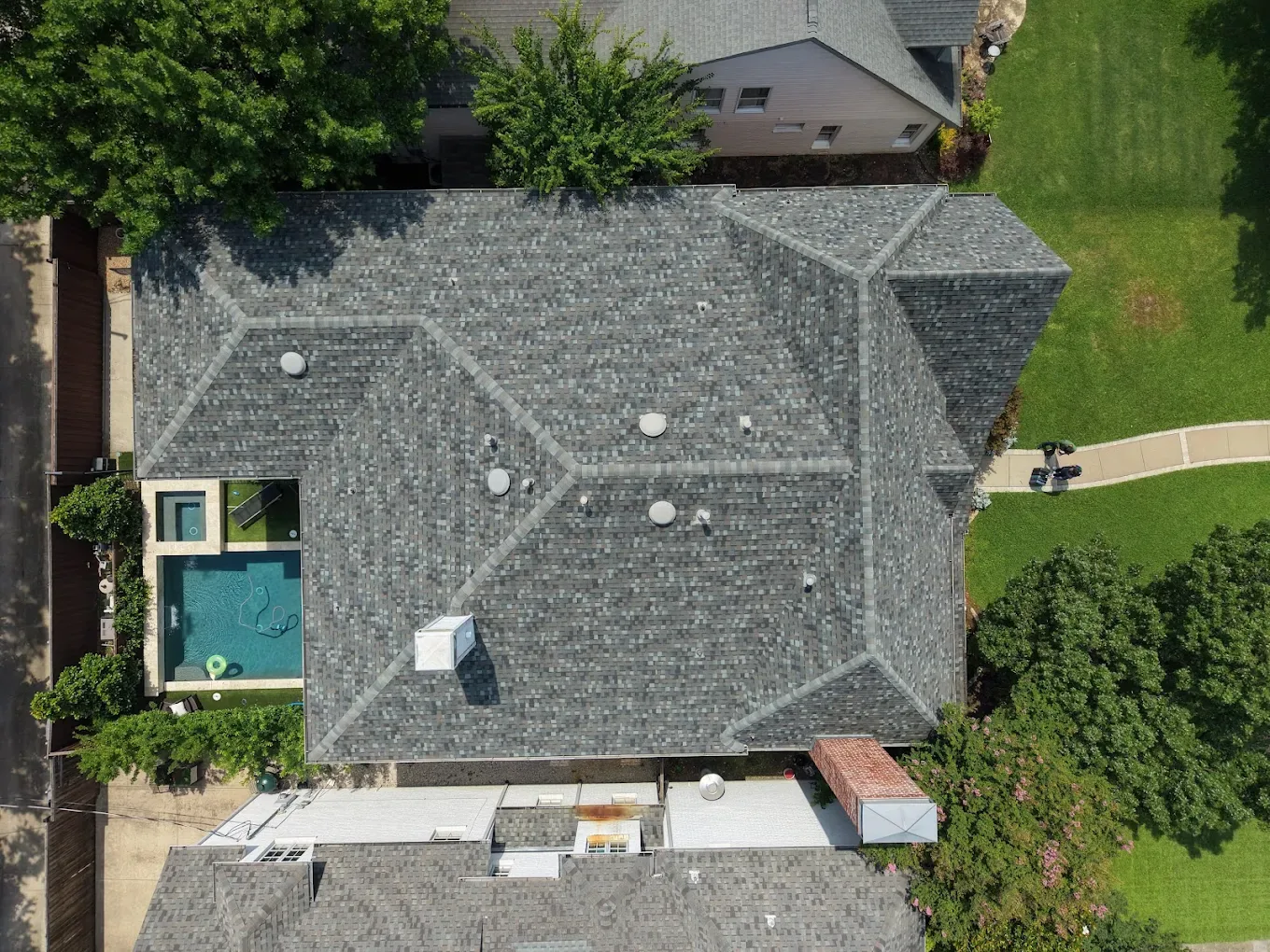 Overhead drone view of a completed architectural shingle roof on a large Dallas–Fort Worth home with a pool