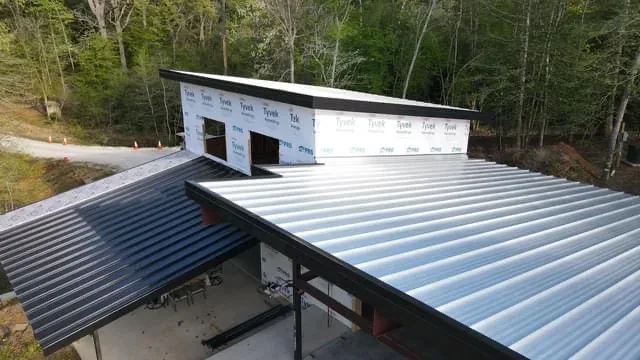 Corrugated metal roof panels being installed on a new steel-framed building