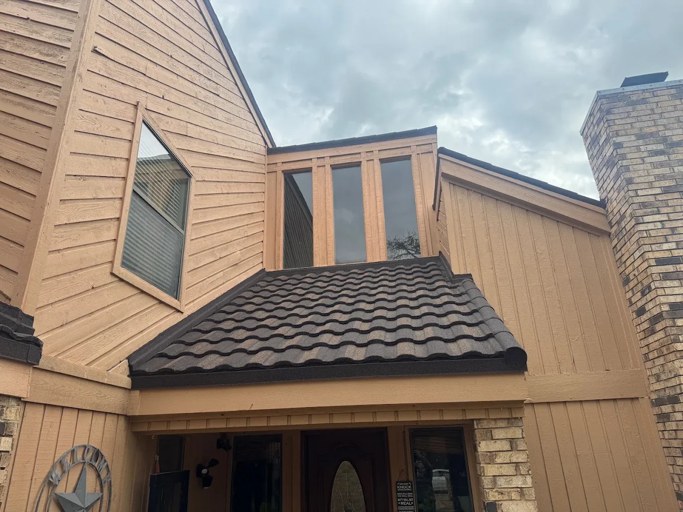 Dark stone-coated steel barrel tile roof over the entry of a Dallas–Fort Worth home